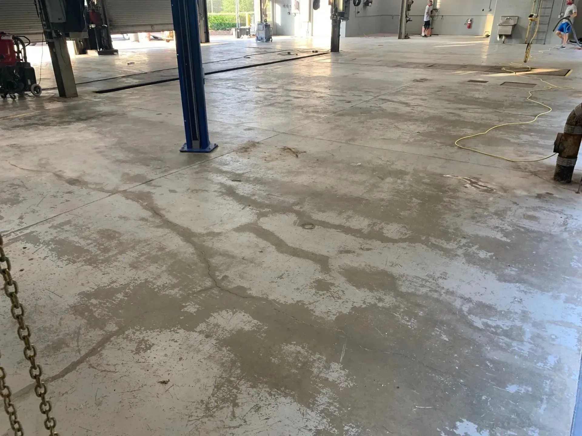 Cracked concrete floor in a garage with car lifts.