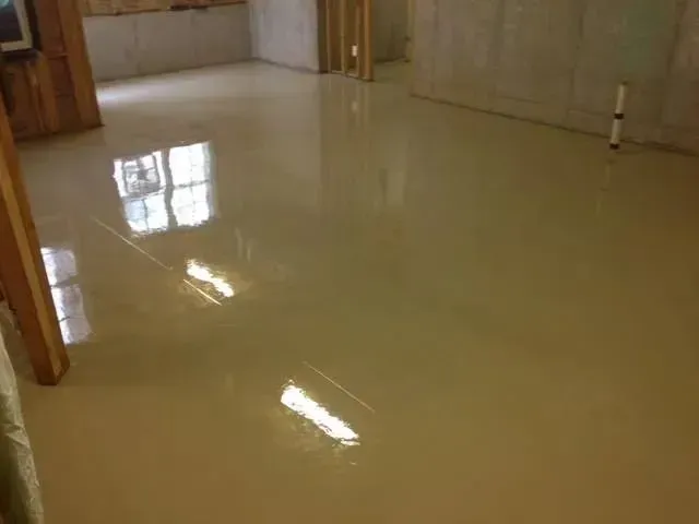 Light tan, polished concrete floor in a basement room, reflecting sunlight.