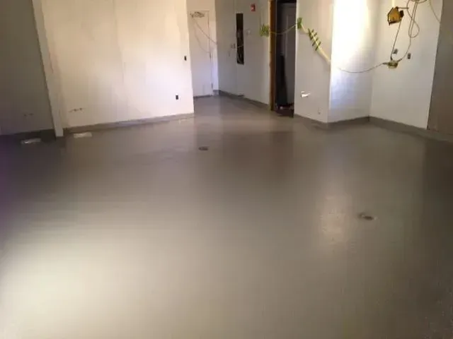 Empty room with a shiny gray floor, white walls, and an open doorway.