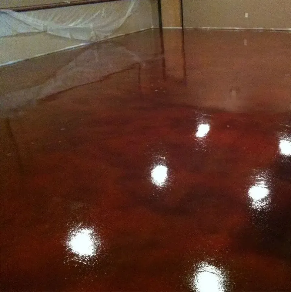 Glossy, reddish-brown epoxy floor reflecting bright lights in an indoor setting.