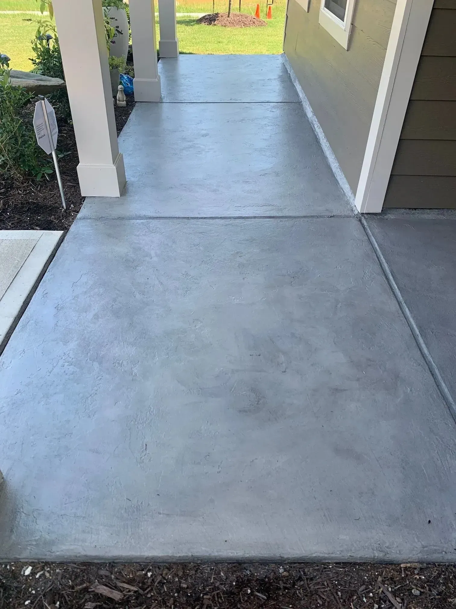 Concrete front porch with light gray finish, leading to a house entrance.