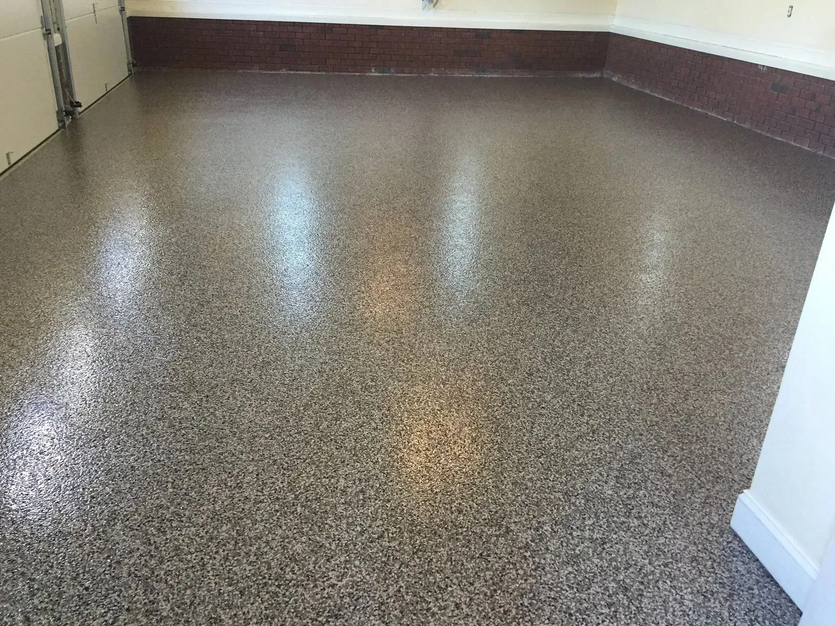 Shiny, speckled, epoxy-coated garage floor in shades of gray, brown, and white.
