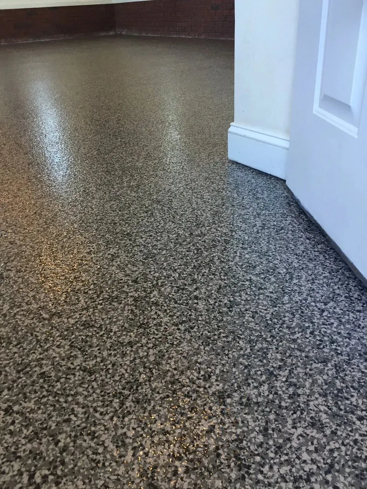 Speckled epoxy floor in a room, with white trim and door.