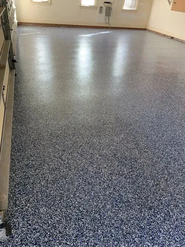 A room with a blue and white speckled epoxy floor. Windows are visible at the top of the wall.