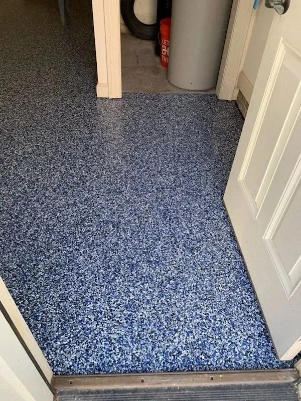 Blue speckled epoxy garage floor seen from doorway.