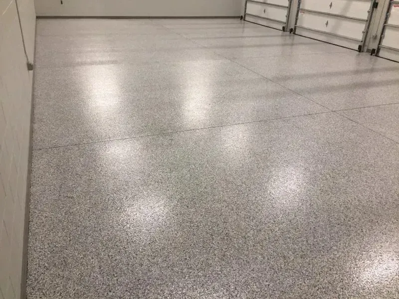 Gray speckled garage floor with bright reflections, near white garage doors.