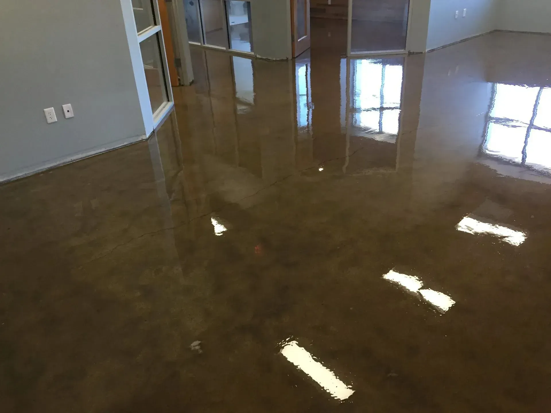 Polished brown floor reflecting bright window light in an office setting.