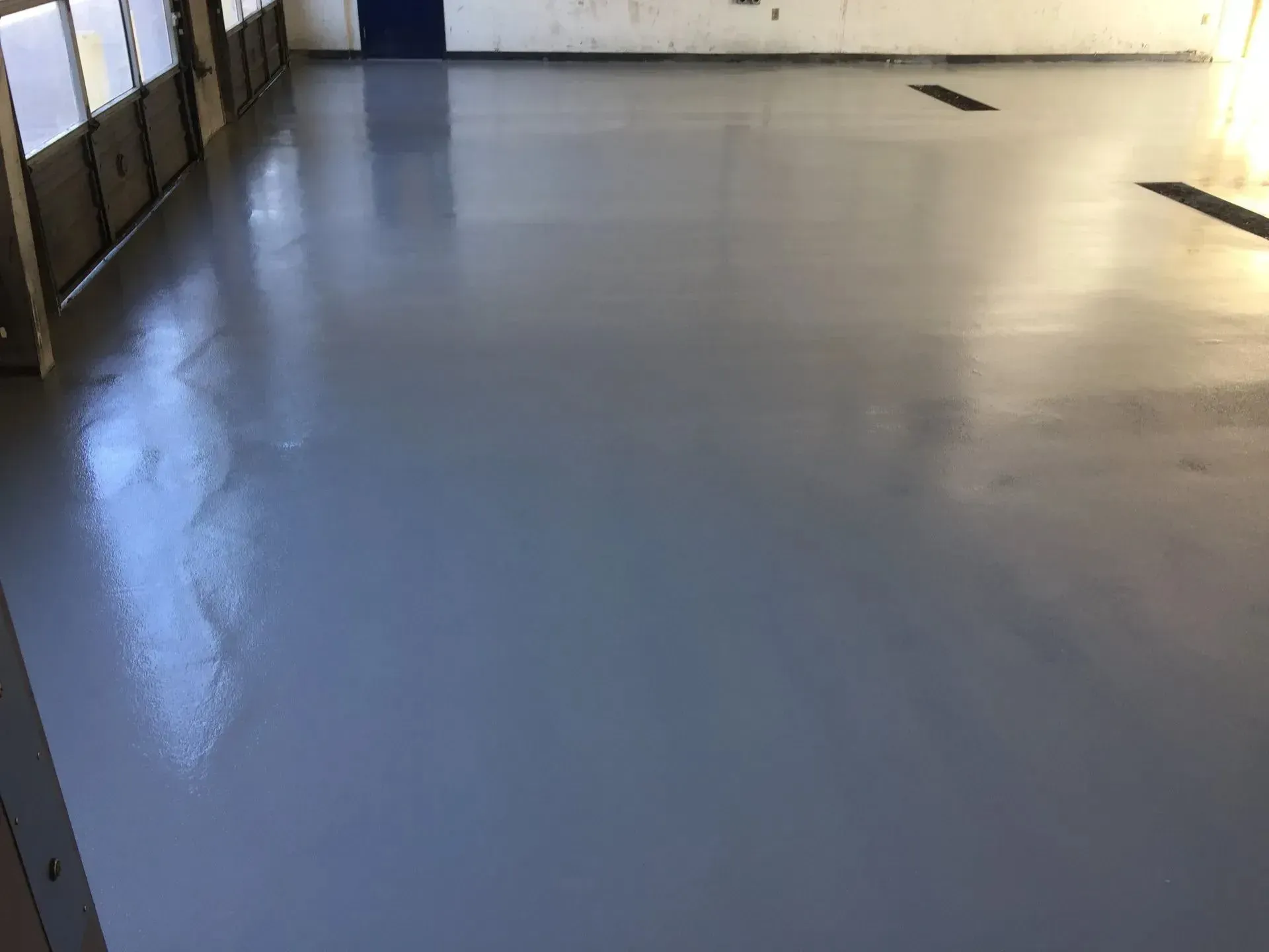 A smooth, gray epoxy floor reflecting light in an open, empty room.