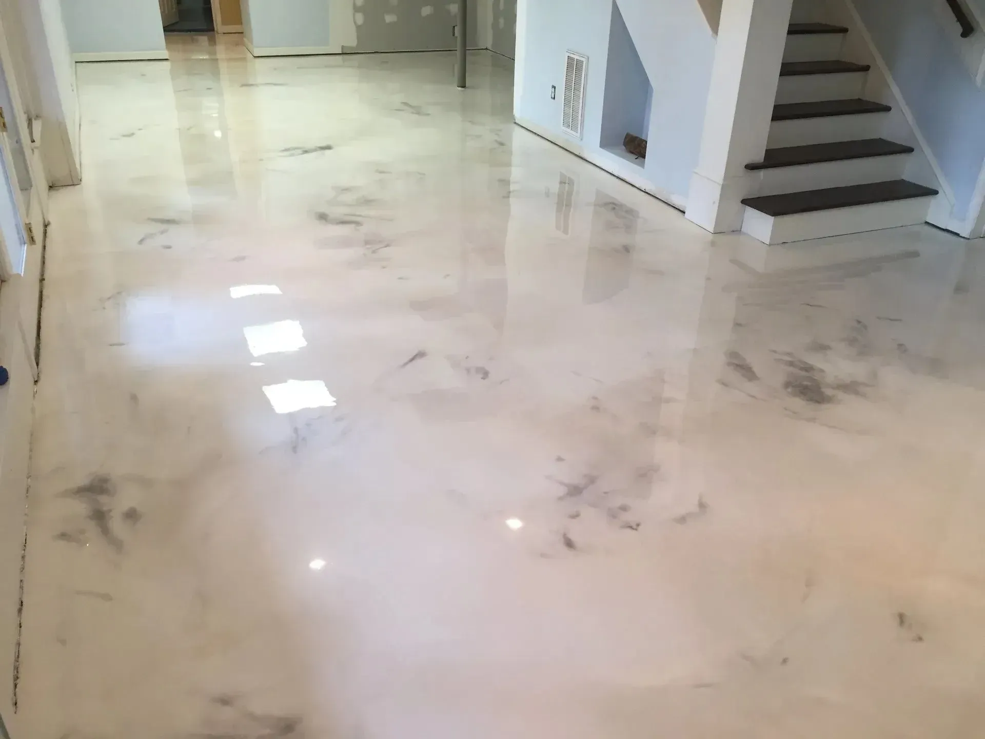 Shiny white and silver epoxy floor in a room, reflecting light.