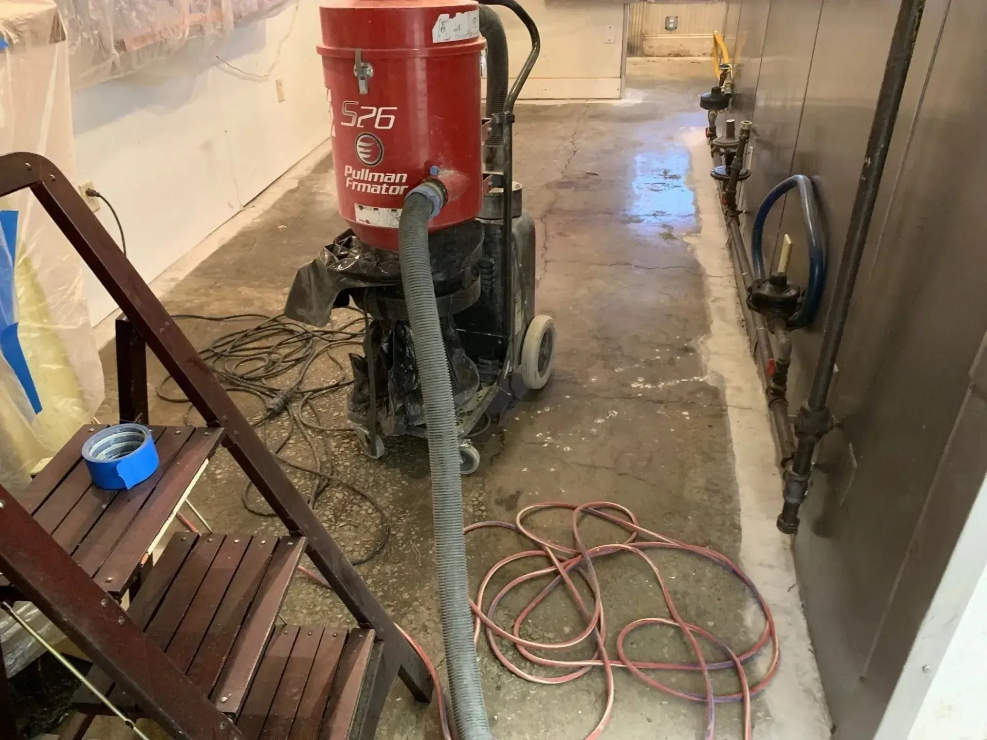 Red dust extraction machine and ladder in a construction zone.