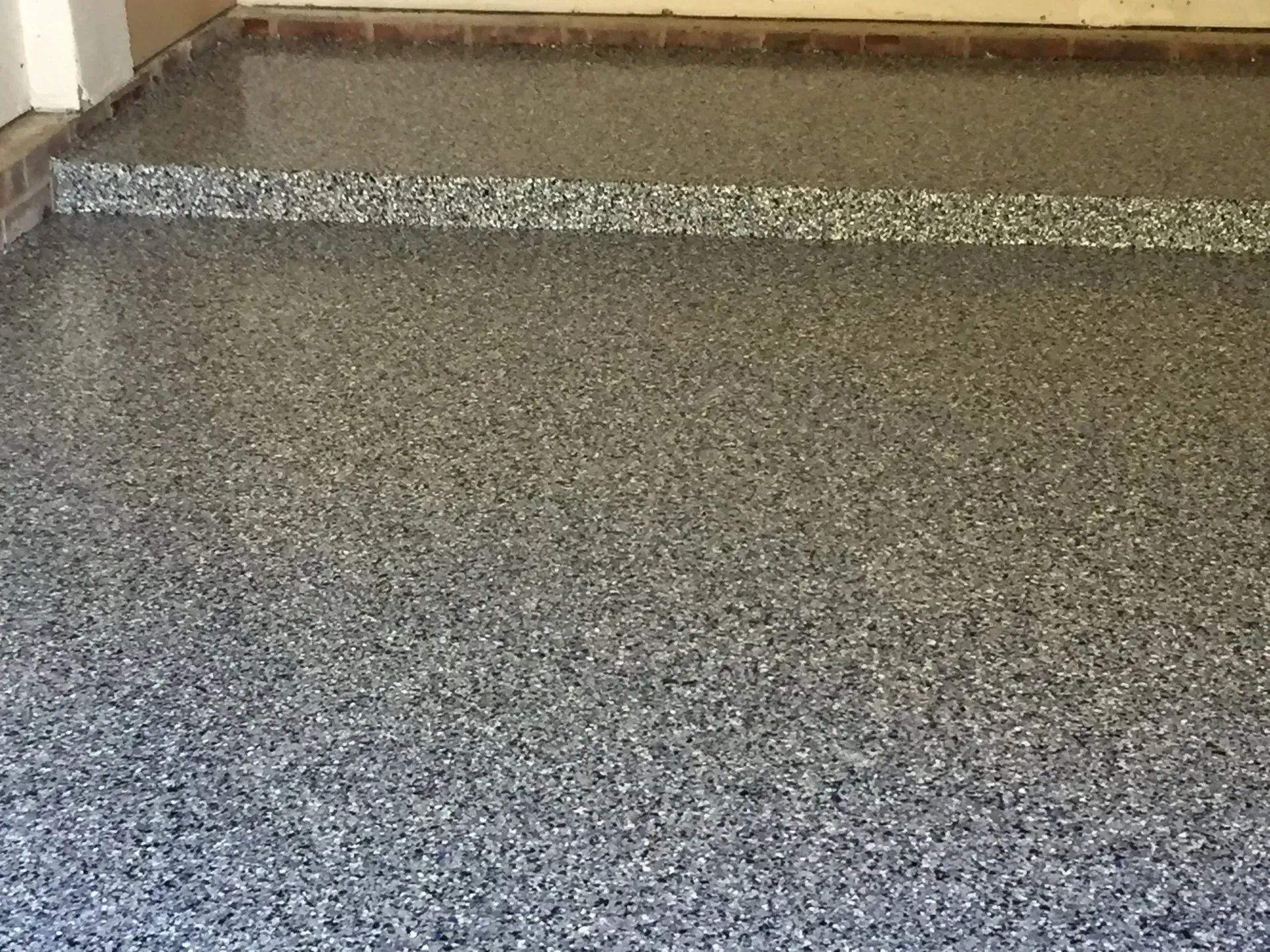 Epoxy garage floor speckled with gray, black, and white chips.