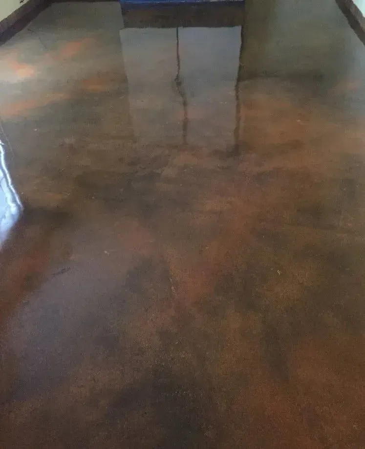 Brown and copper stained concrete floor with glossy finish, reflecting a window.