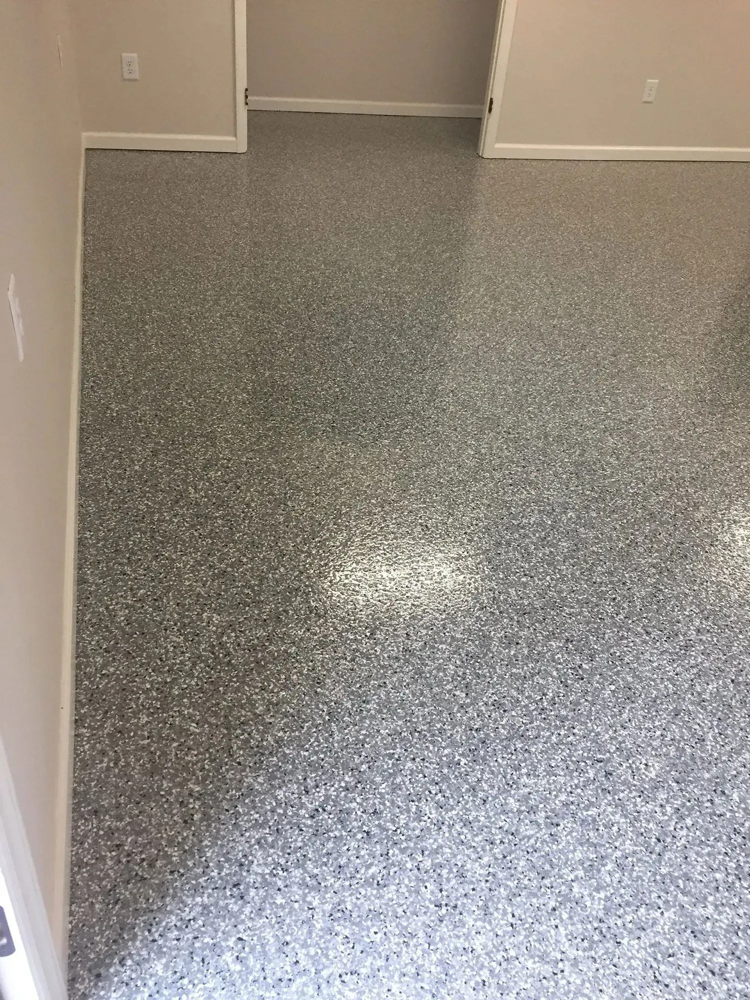 Gray speckled epoxy flooring in a room with neutral walls and doorway.