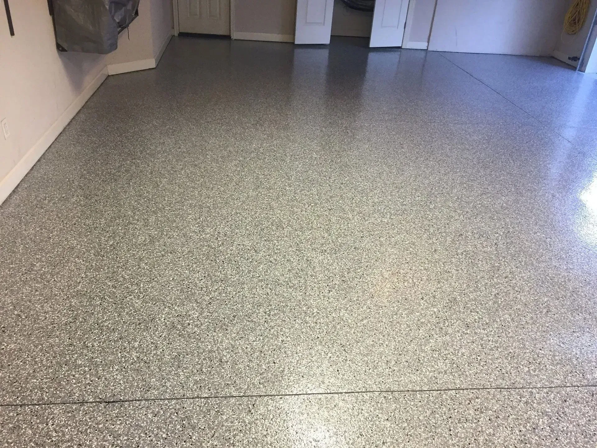 A garage floor with a shiny, speckled epoxy coating in shades of gray.