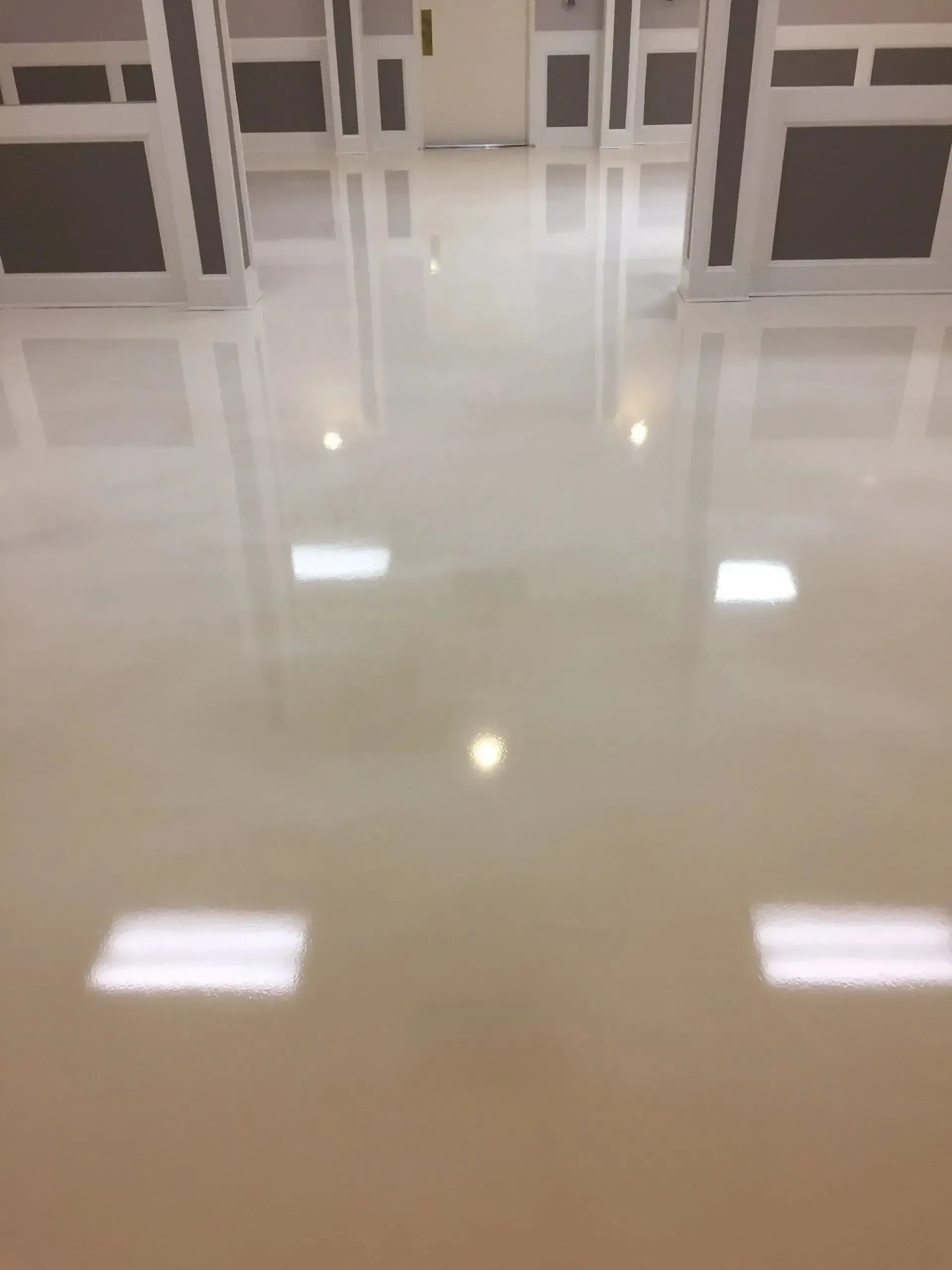 Glossy, light-colored floor reflecting overhead lights and a bright white room with dark accents.