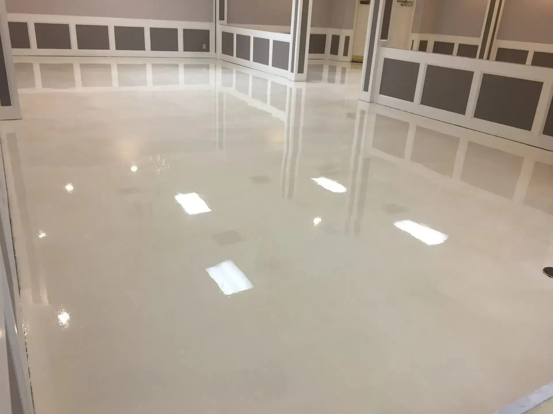 Light-colored glossy floor reflects overhead lights and wall panels in a well-lit interior.
