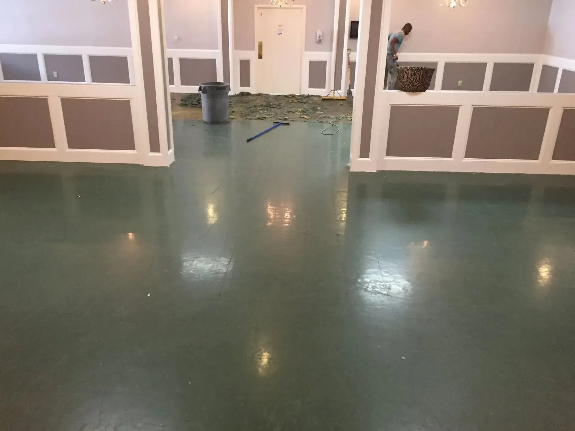 Interior view of a room with a shiny green floor, gray walls, and white trim.