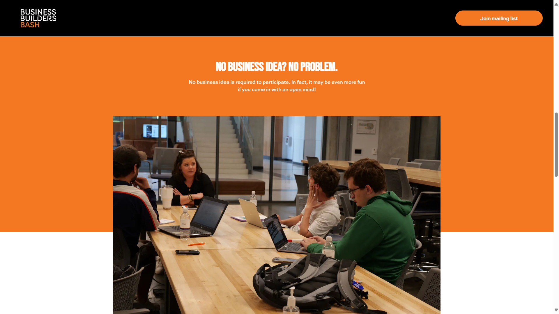 A group of people are sitting at a table with laptops.