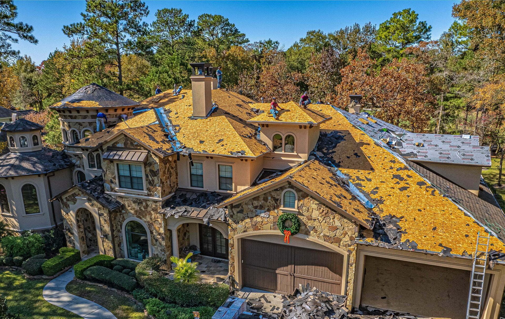 An aerial view of a large house with a roof that is being repaired.