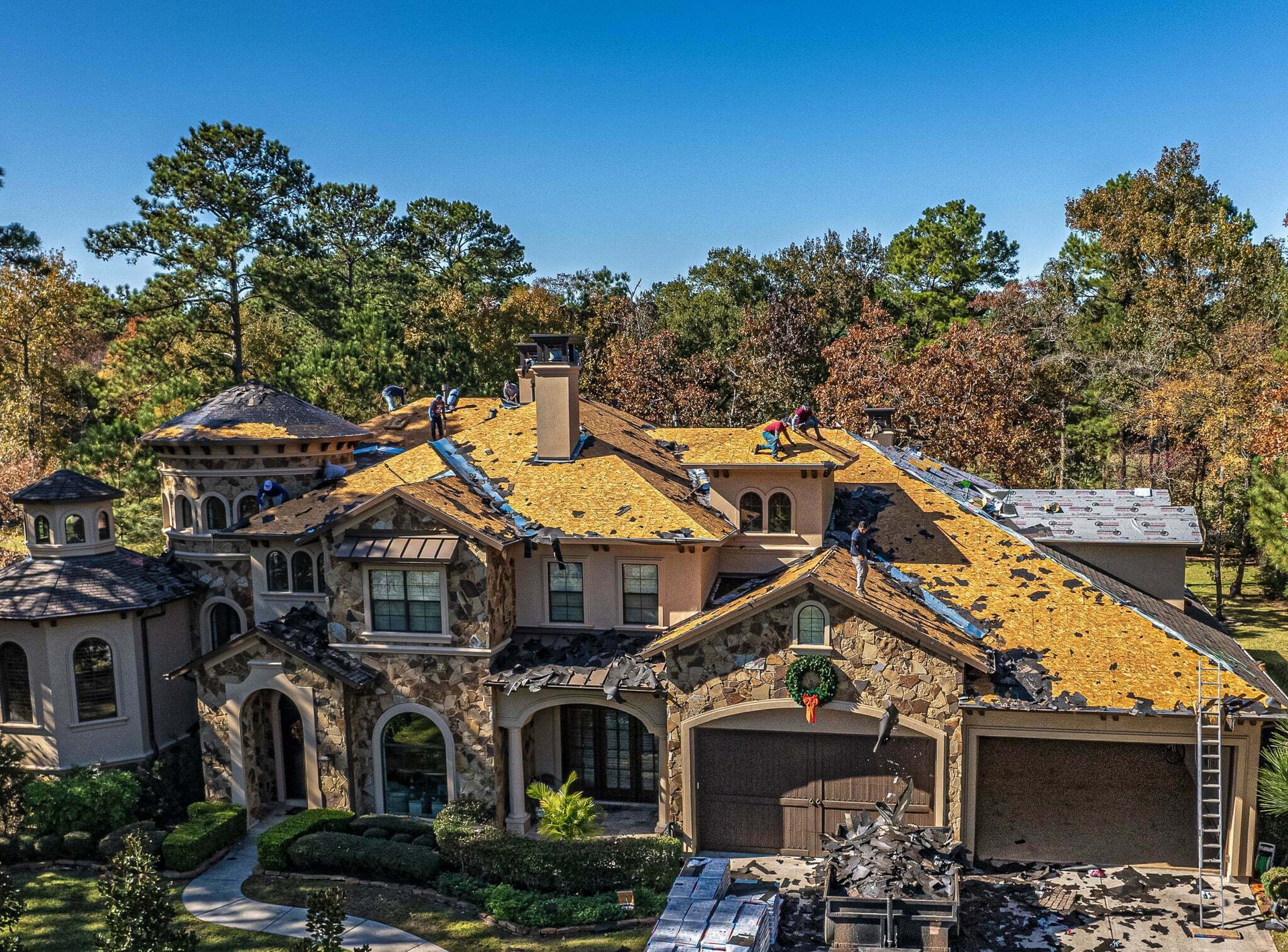 An aerial view of a large house with a roof that is being installed.