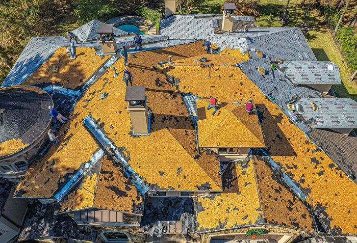 An aerial view of a roof being installed on a large house.