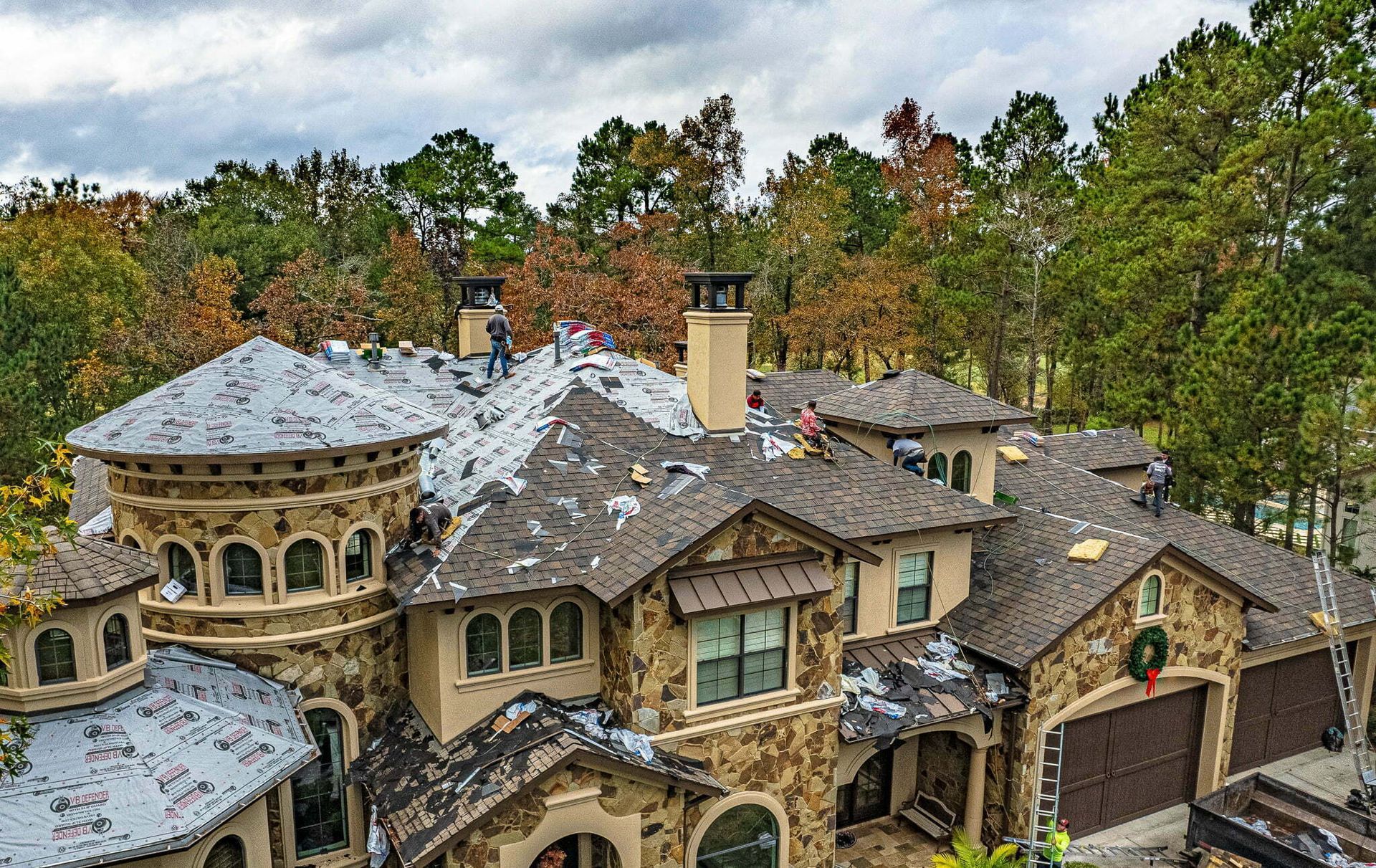 An aerial view of a large house with a roof that is being repaired.
