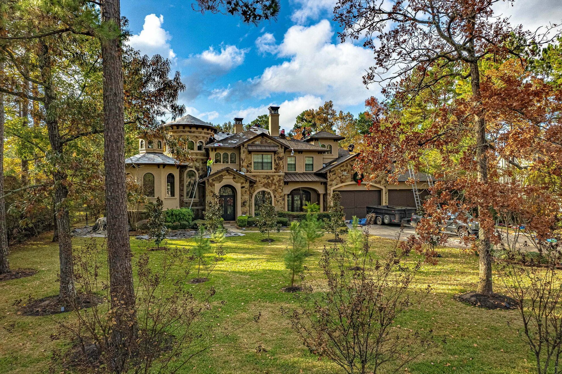 A large house is surrounded by trees and grass in the middle of a forest.