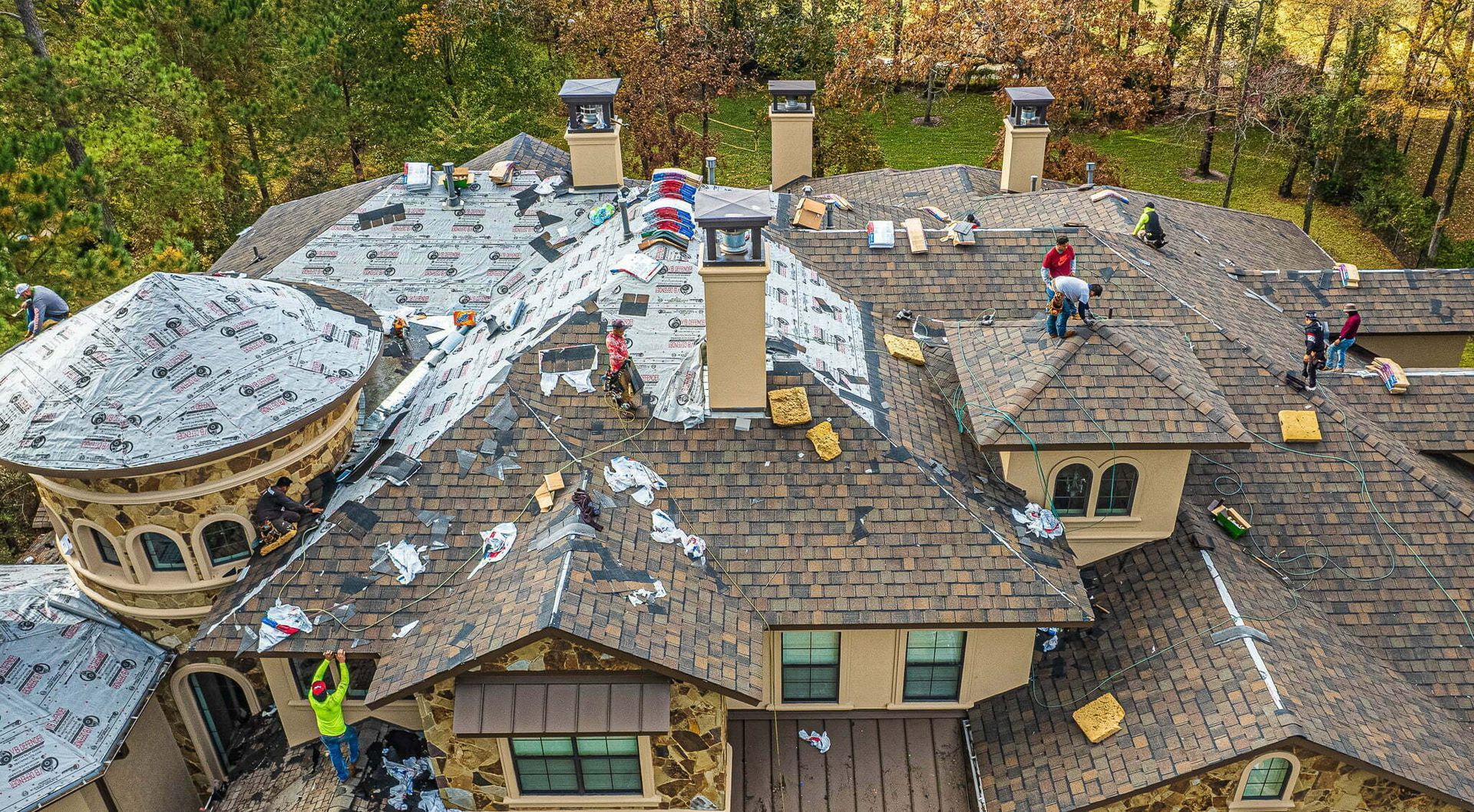 A group of people are working on the roof of a large house.