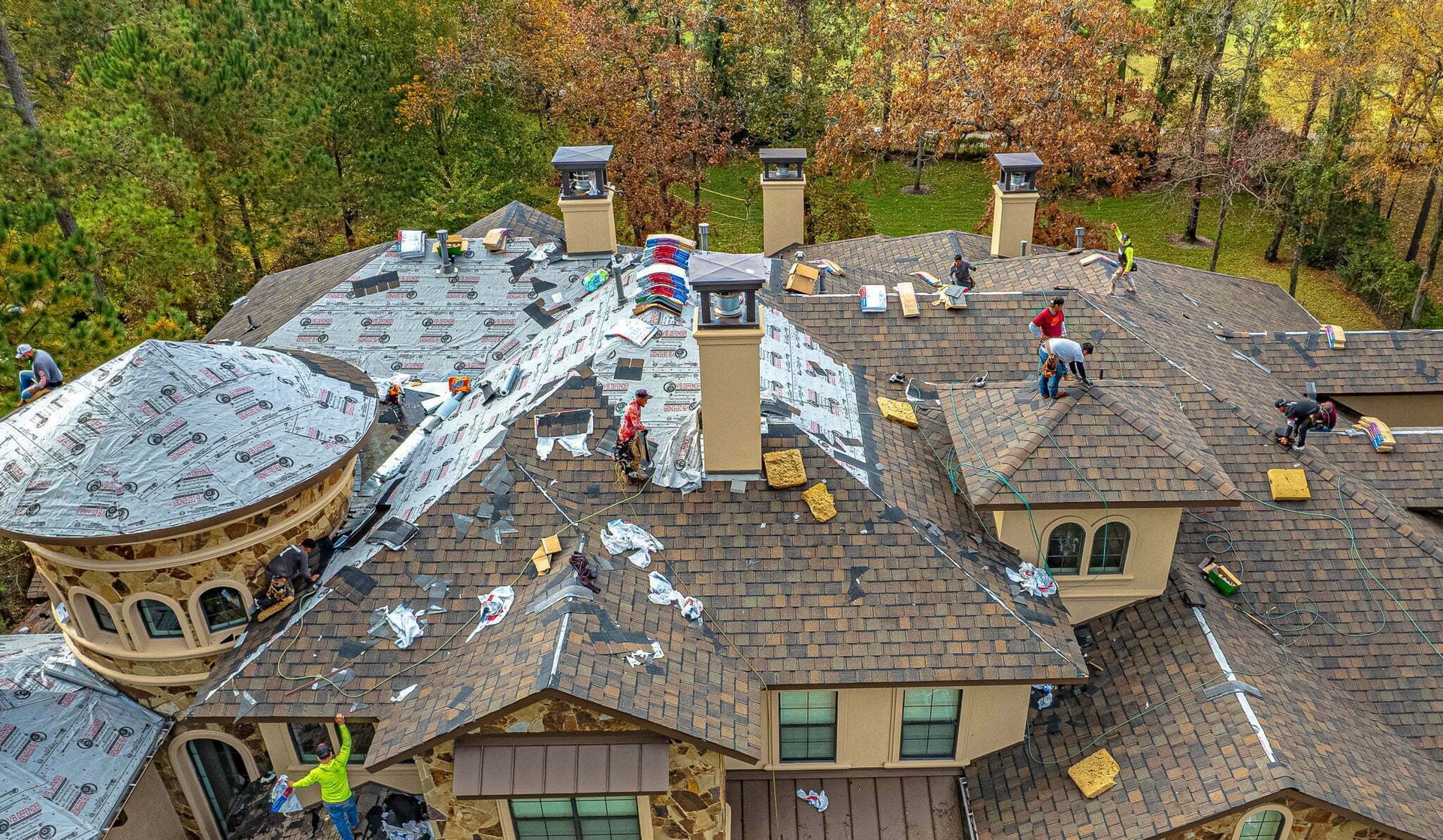 A group of people are working on the roof of a large house.