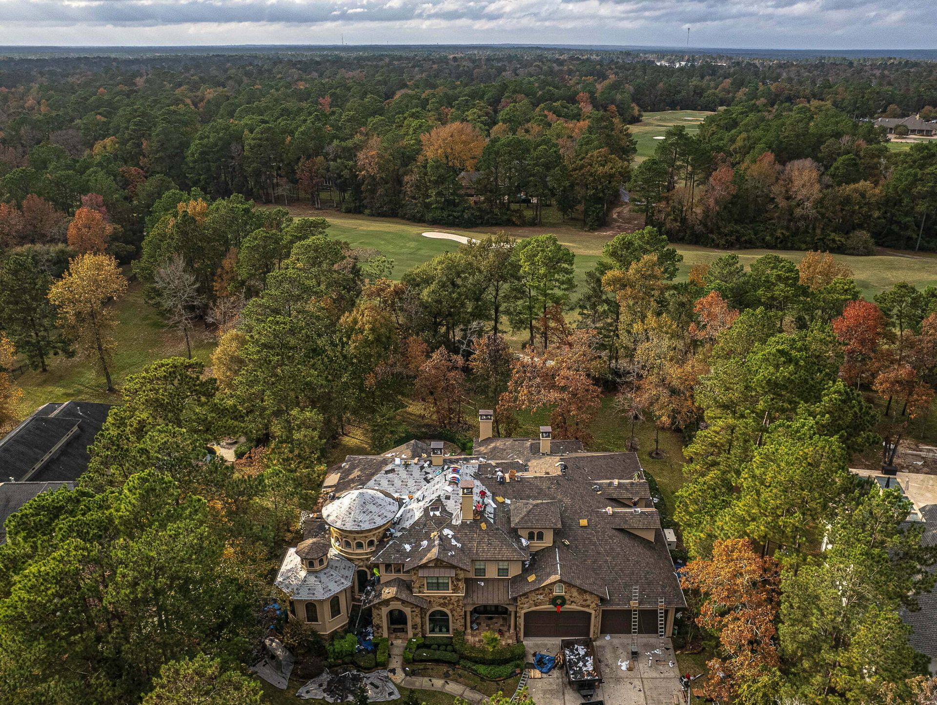 An aerial view of a large house surrounded by trees and a golf course.