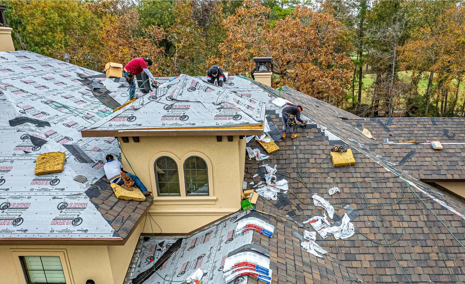 A group of men are working on the roof of a house.