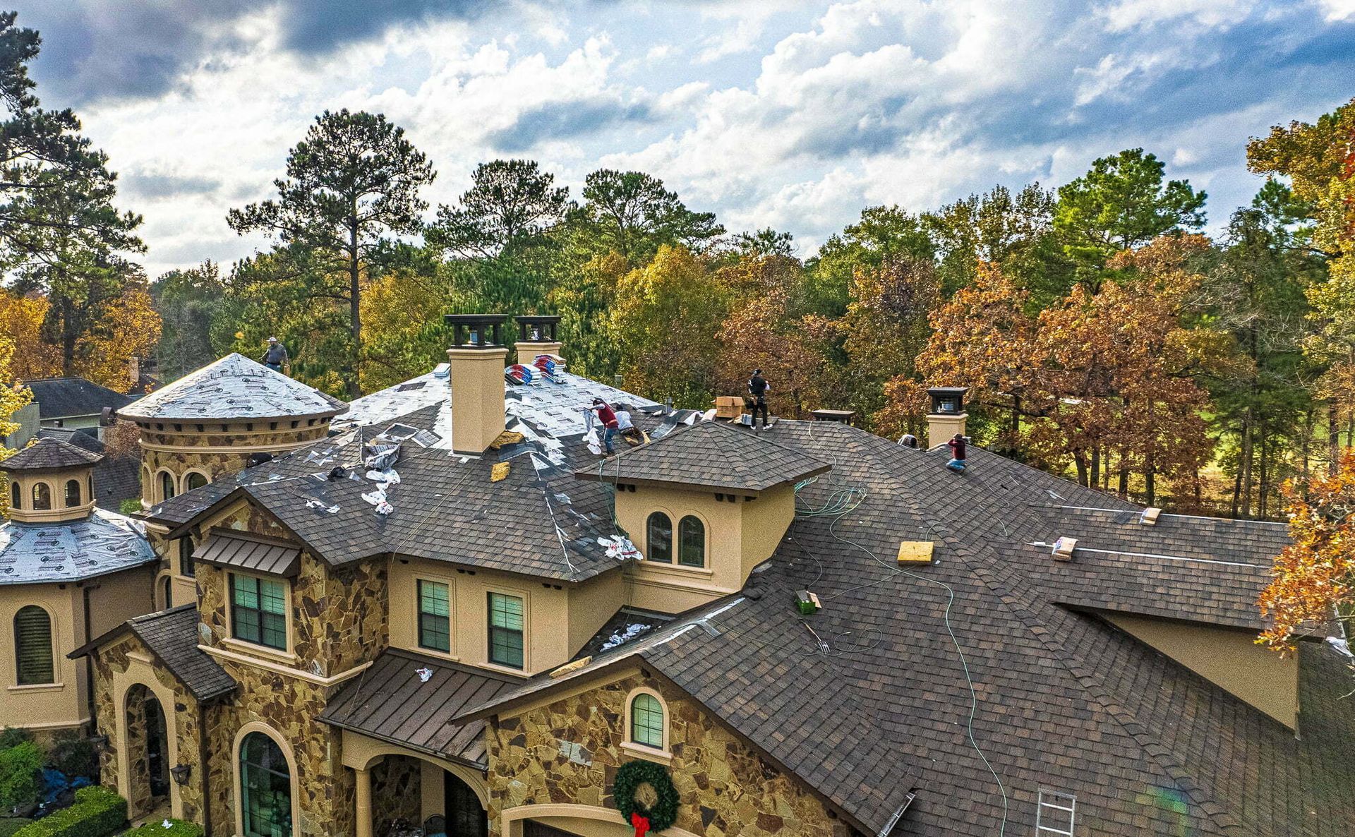 An aerial view of a large house with a roof being repaired.
