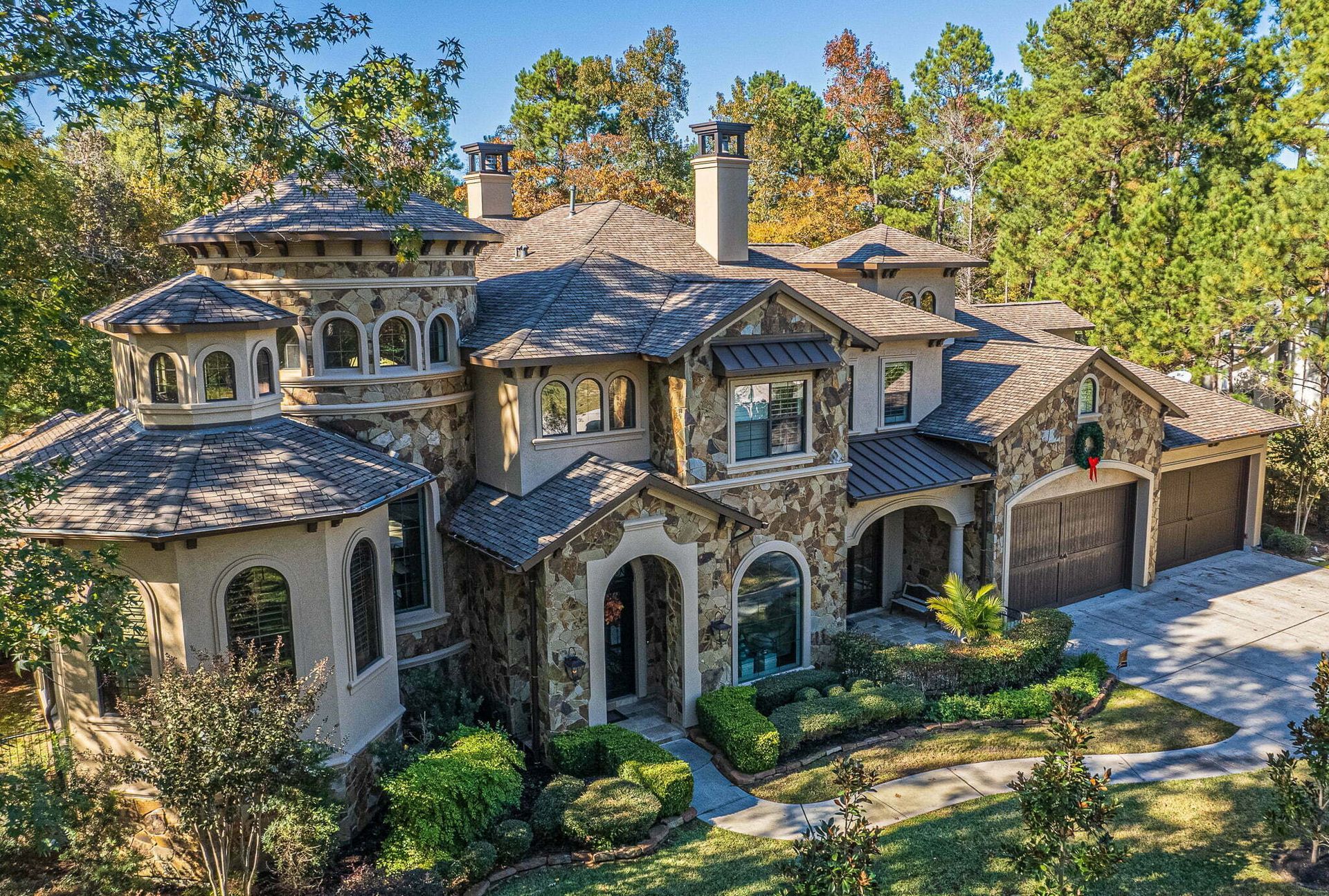 A large house with a wreath on the front of it is surrounded by trees.
