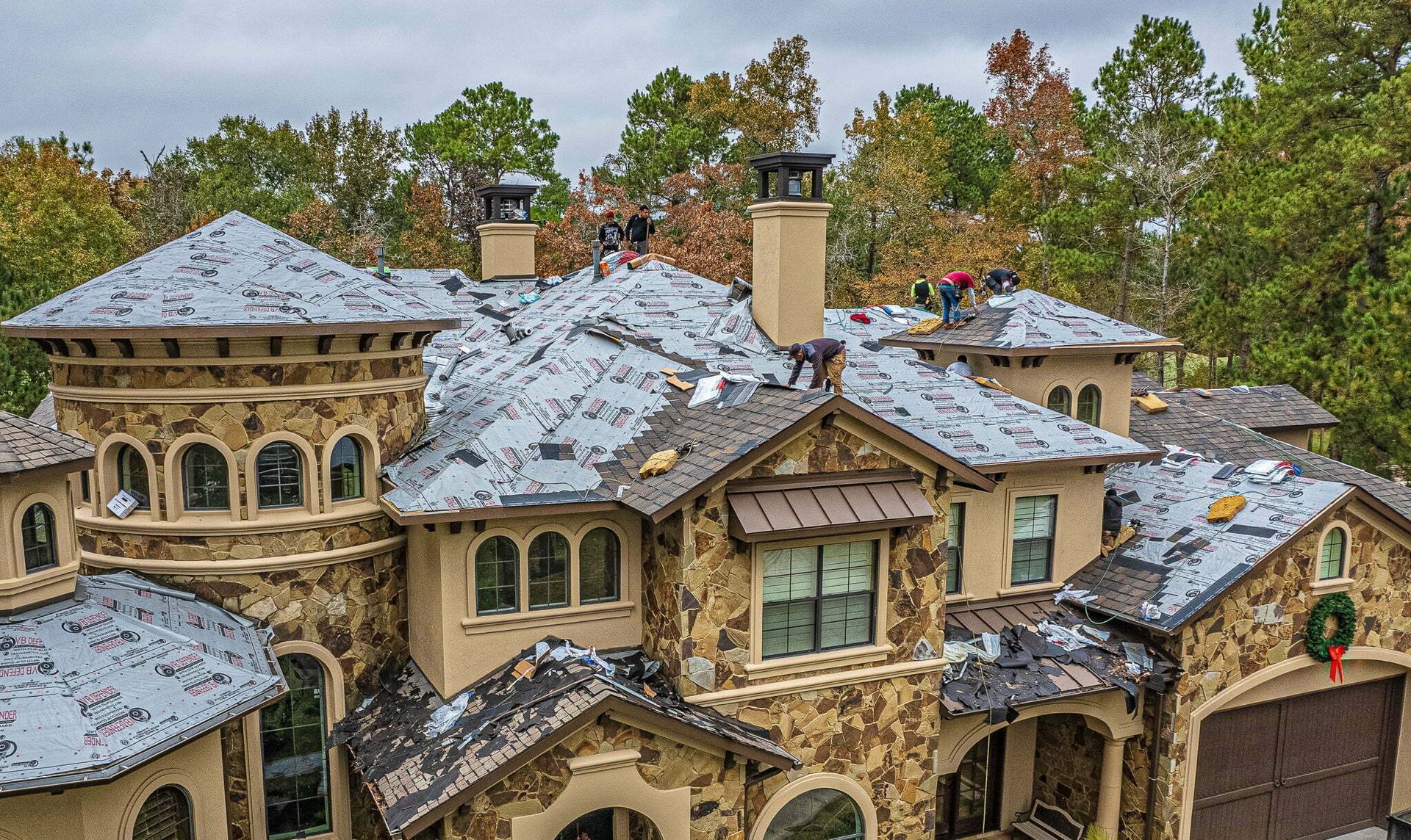 An aerial view of a large house with workers on the roof.