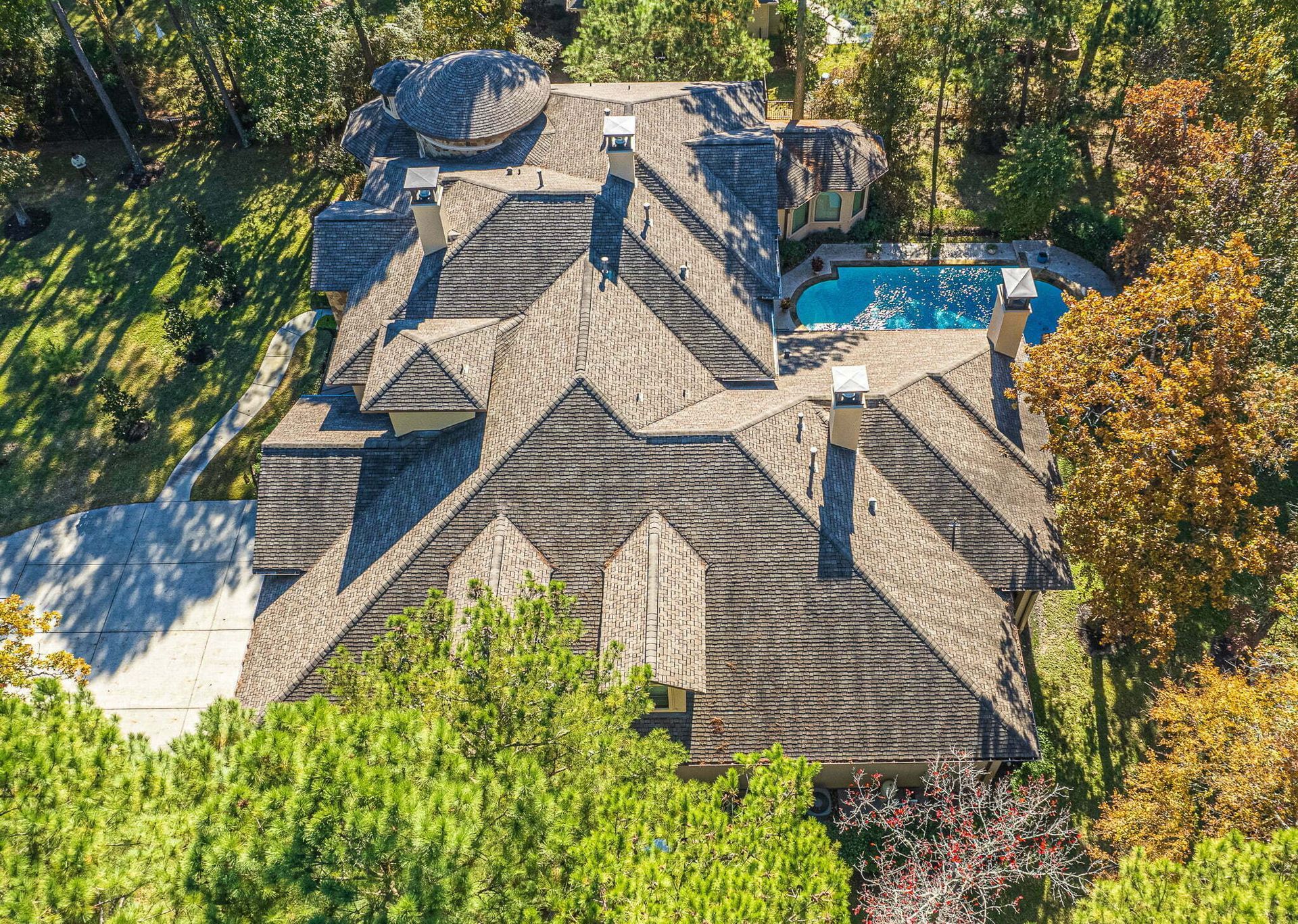 An aerial view of a large house with a pool surrounded by trees.