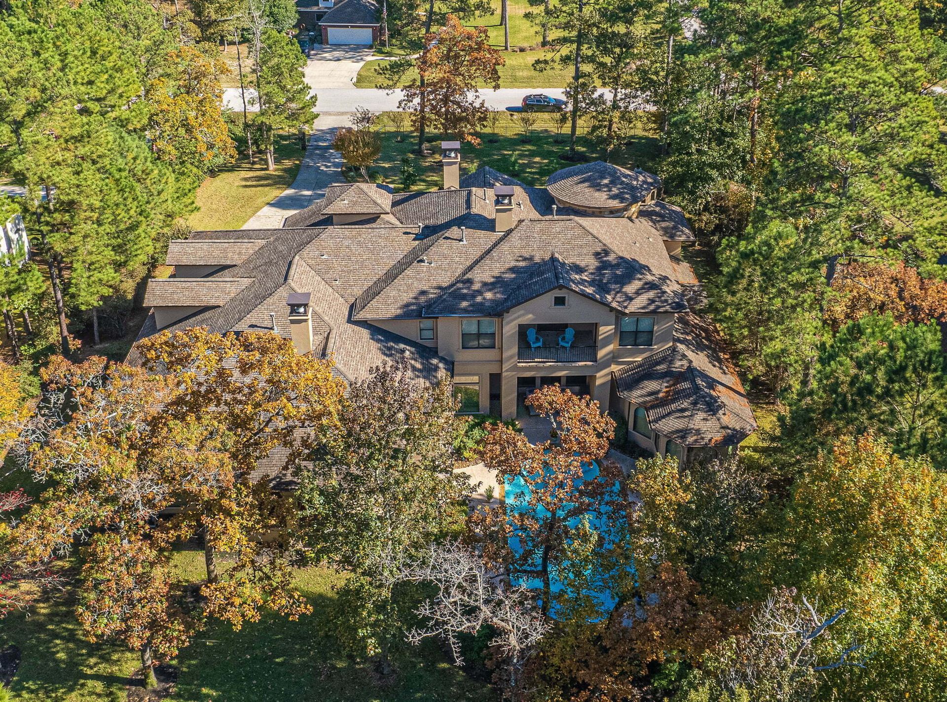 An aerial view of a large house surrounded by trees and a pool.