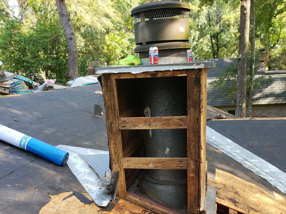 A chimney is being removed from the roof of a house