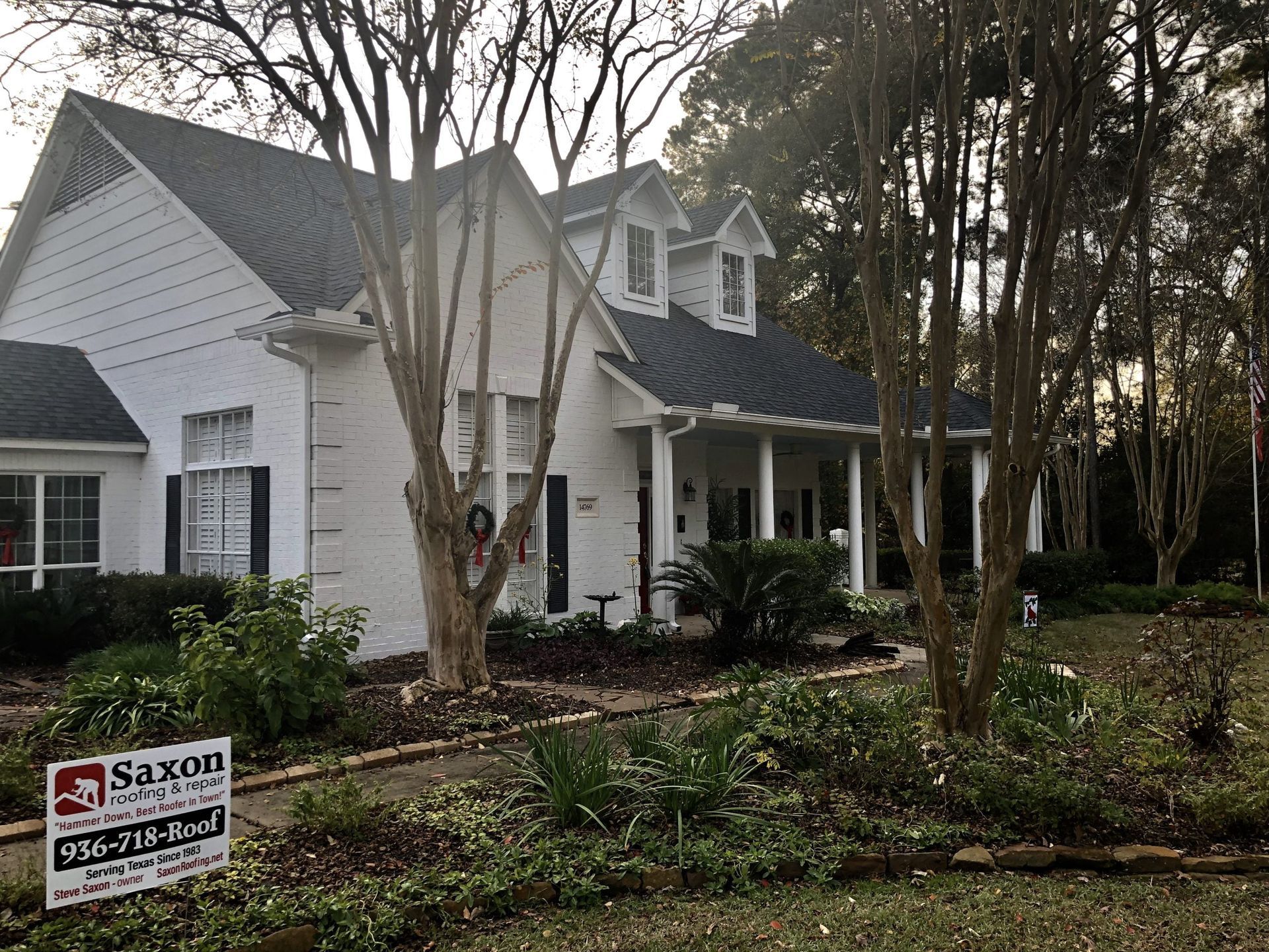 A white house with a black roof is for sale.