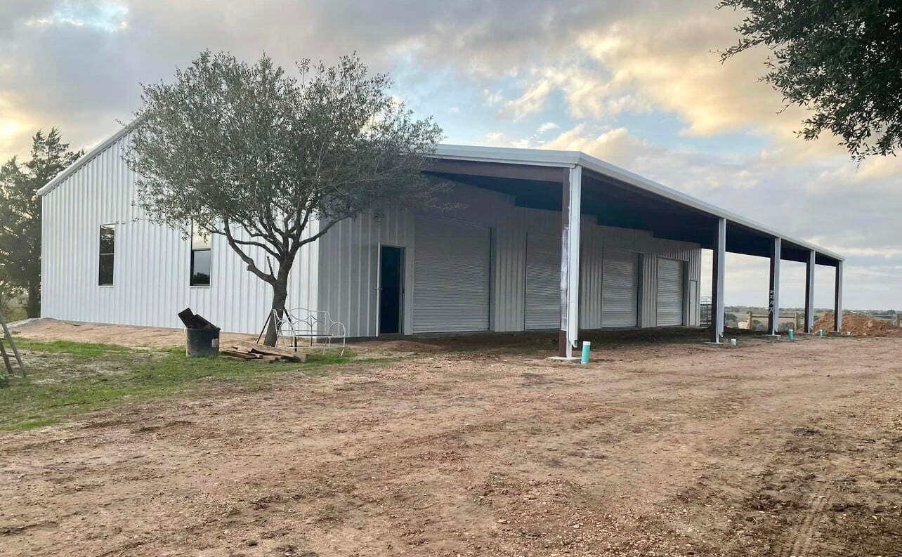 A large white building with a covered porch and a tree in front of it.