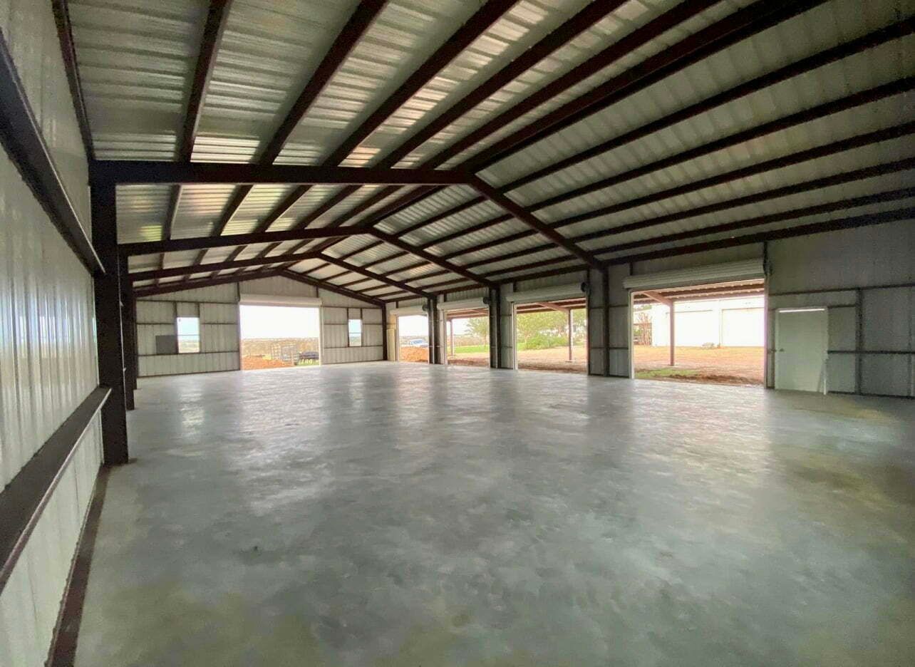 A large empty warehouse with a concrete floor and a metal roof.