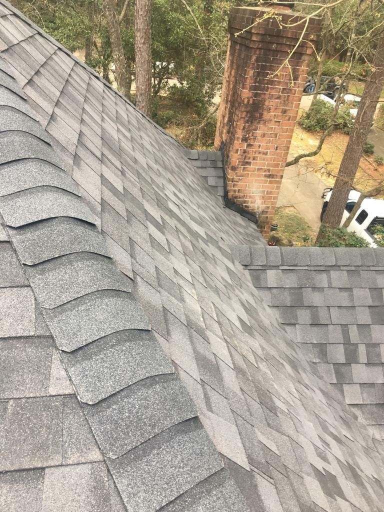 A close up of a roof with shingles and a chimney.