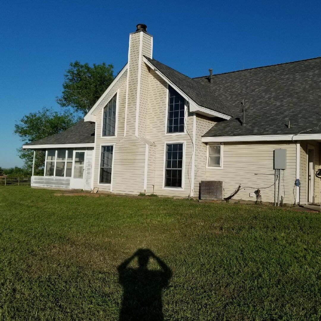 A shadow of a person is cast on the grass in front of a house