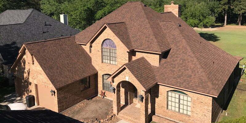 An aerial view of a large brick house with a brown roof.