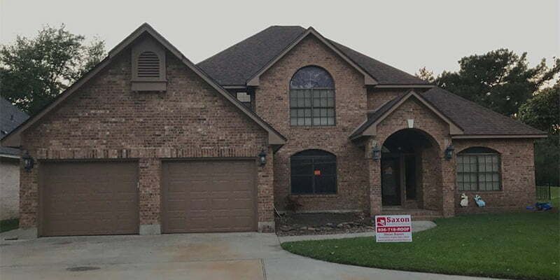 A large brick house with a for sale sign in front of it