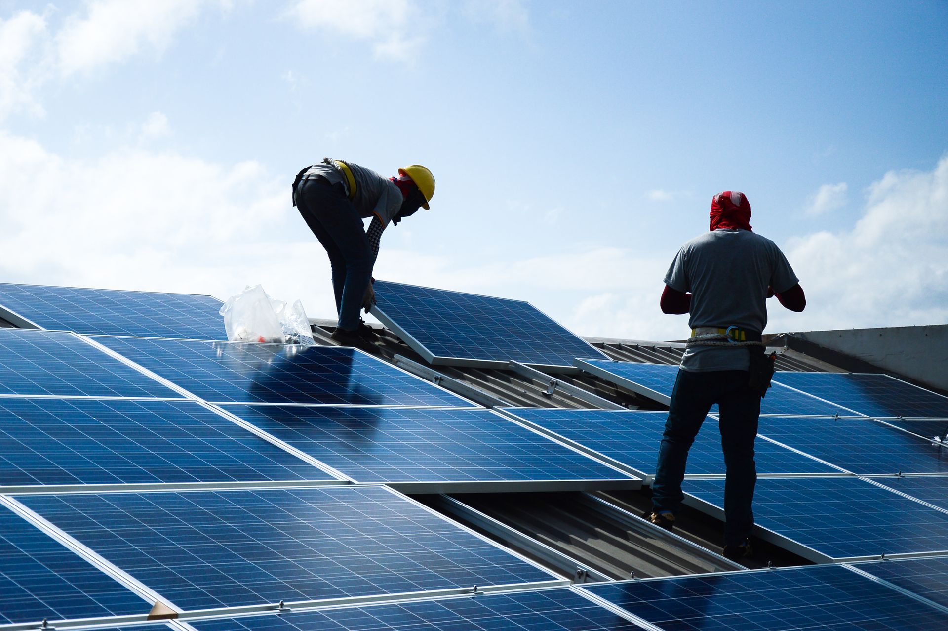 Two men are installing solar panels on a roof.