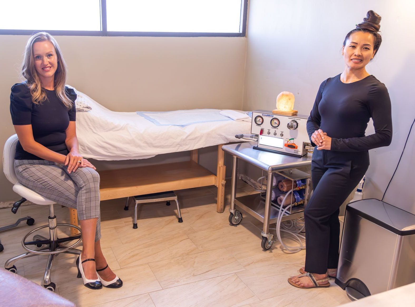 Two women are standing next to each other in a room with a bed.