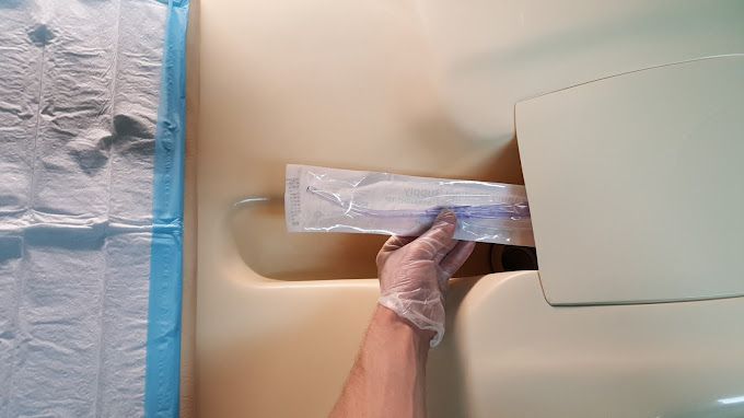 A person is holding a plastic bag in their hand in a bathroom.