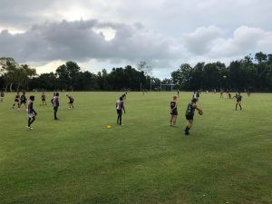 People in sportswear on a grassy field, trees in the background, overcast sky.