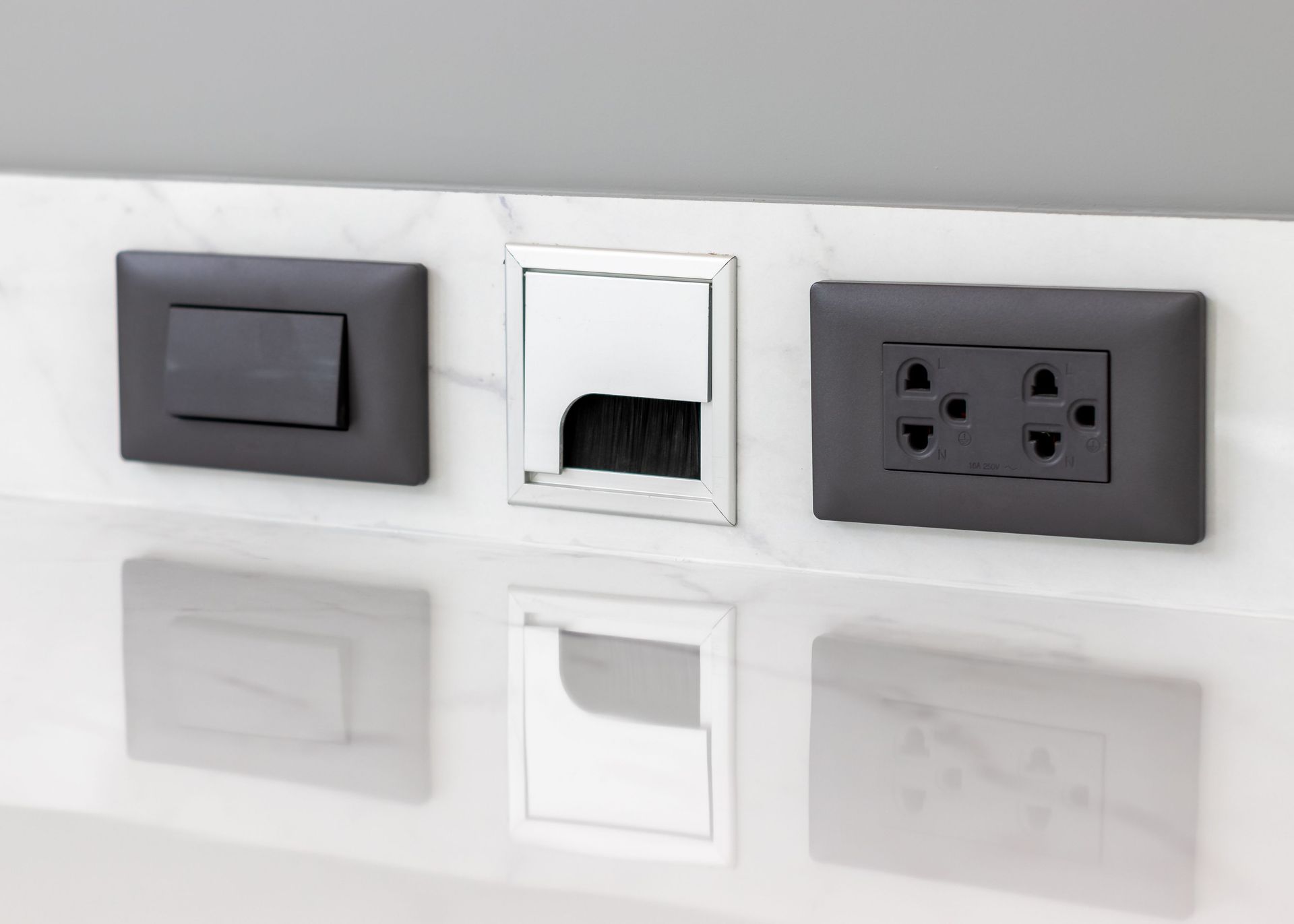 A close up of three electrical outlets and a switch on a wall.
