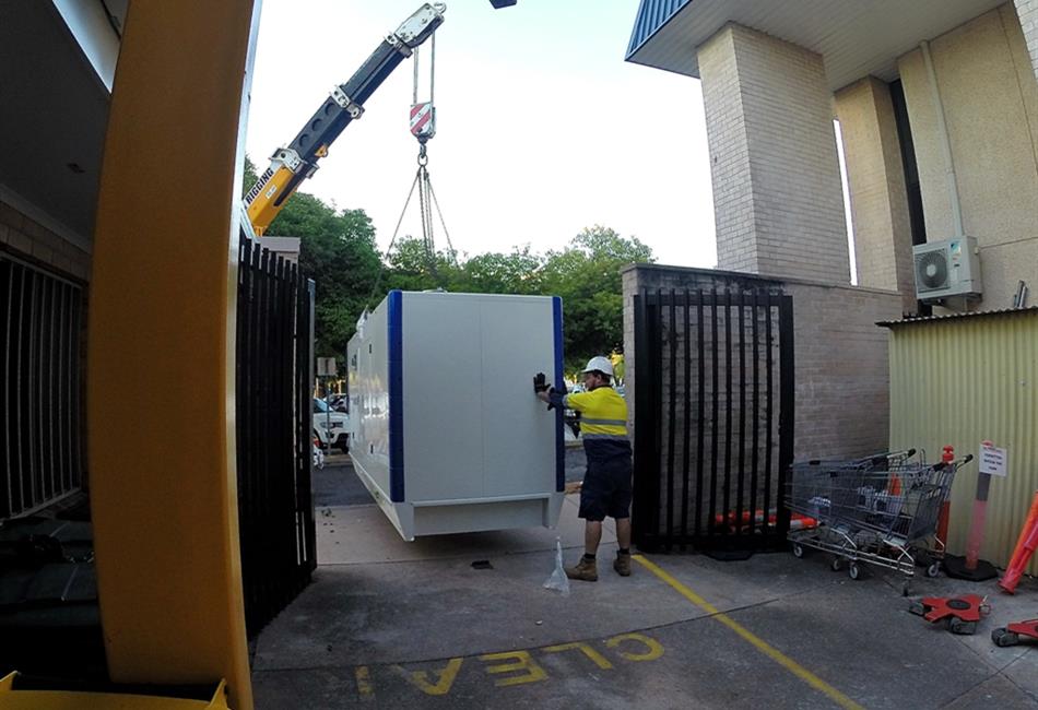 a crane is lifting a white container into a parking lot